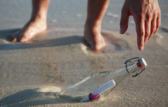 Hand reaching for a message in a bottle